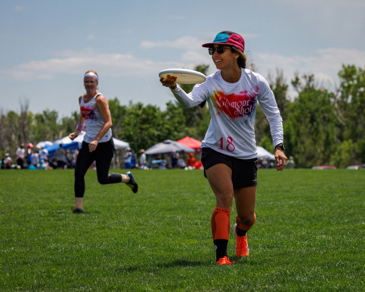 Cara throwing a disc mid-play in an ultimate frisbee game
